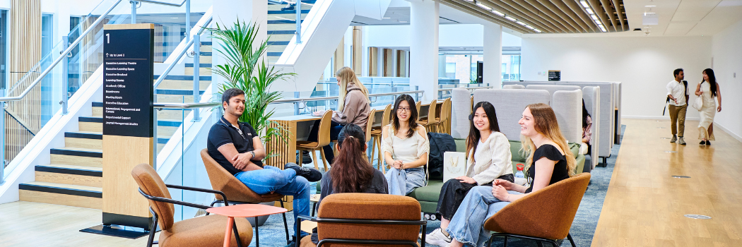 Smiling students sitting in casual meeting area at Waterside building, Business School