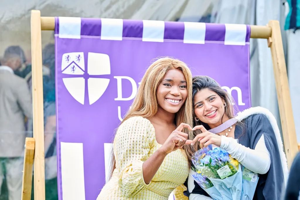 Two students creating a heart shape with hands