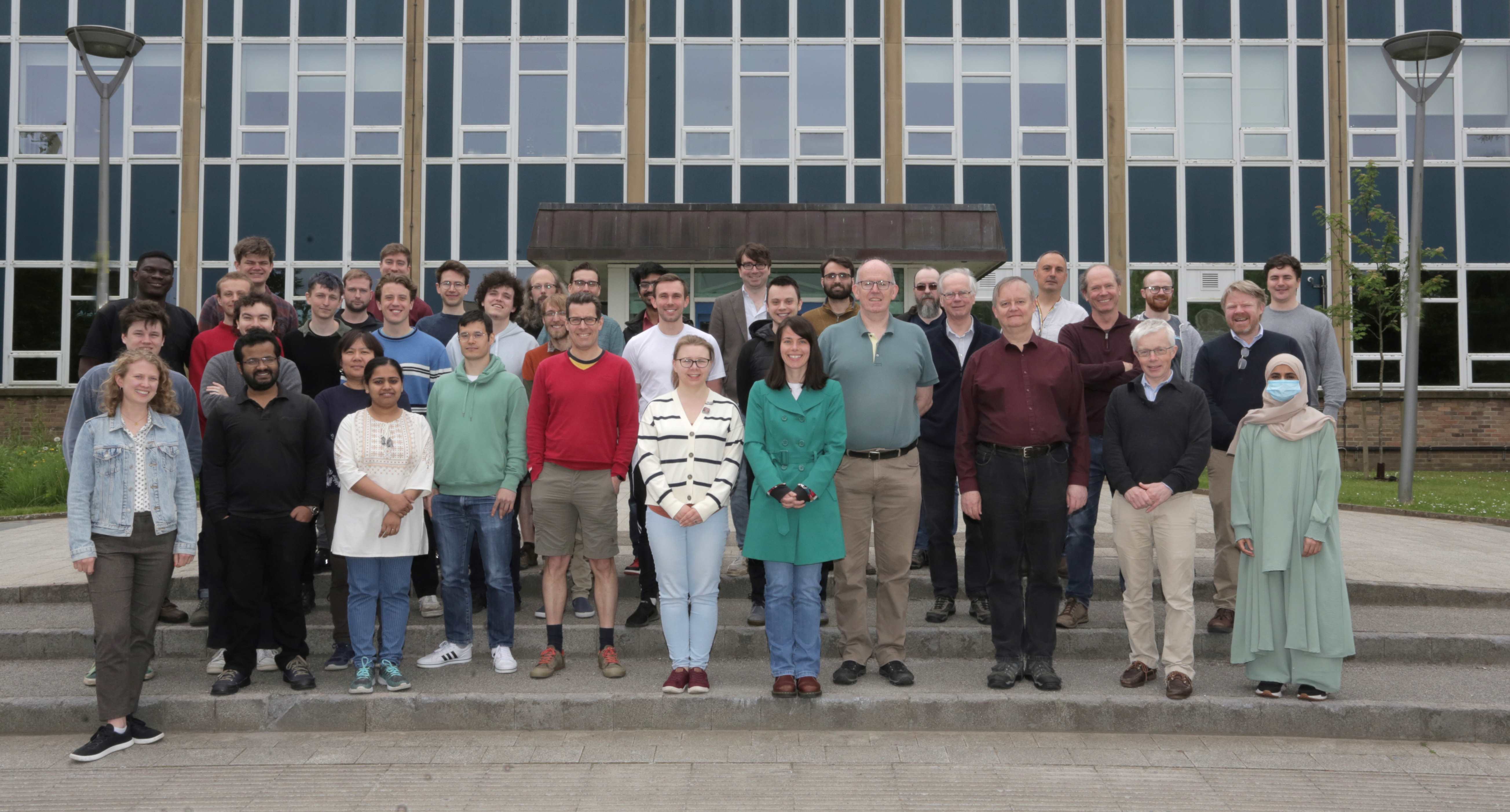 A group photo of the Quantum Light and Matter Group at Durham University standing on a set of steps