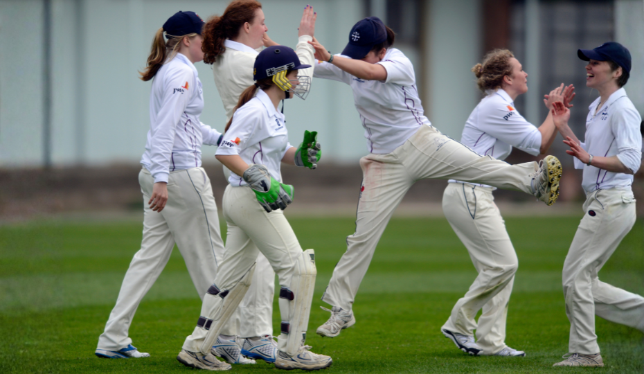 A group of women wearing cricket whites celebrating after a match.