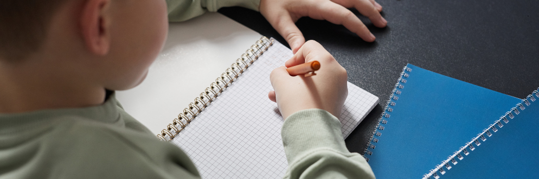 A school child writing in an exercise book.