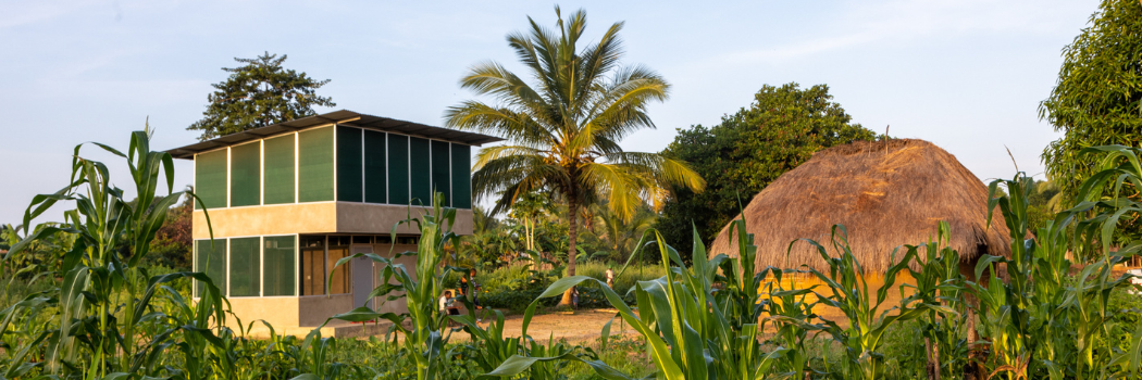 Two-storey Star Home next to a traditional mud-walled house.