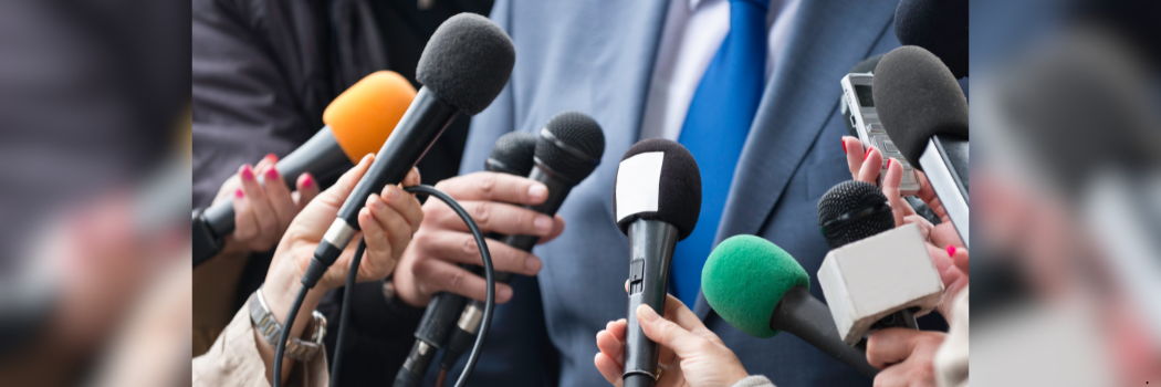 Cluster of press microphones being held around an unidentified person