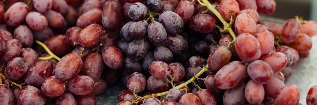 A bunch of red grapes on a metal table top