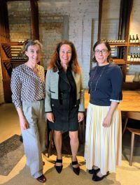 Three women facing the camera and smiling
