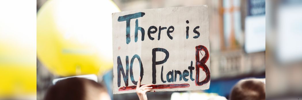 A person holds a sign reading There is No Planet B above their head.