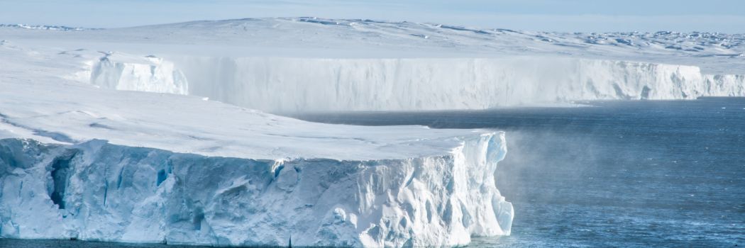 Snow blows from an ice sheet which juts into the sea.