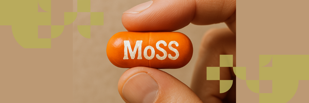 A close-up of an orange tablet capsule with the letters MoSS printed on the front in white held between two fingers