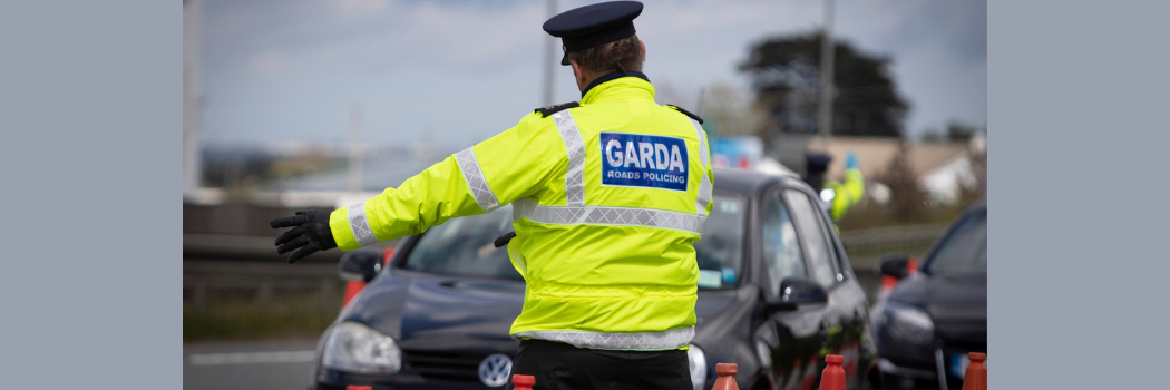 The back of a policeman who is directing traffic while wearing a hi-vis jacket.
