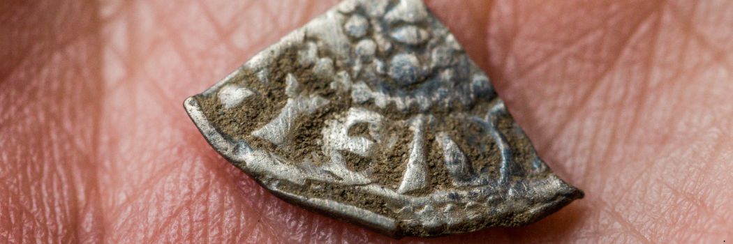 A segment of a silver coin being held in the palm of someone's hand