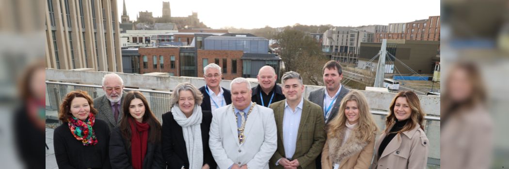 A group of people standing against the backdrop of Durham City with the Castle and Cathedral in the background.