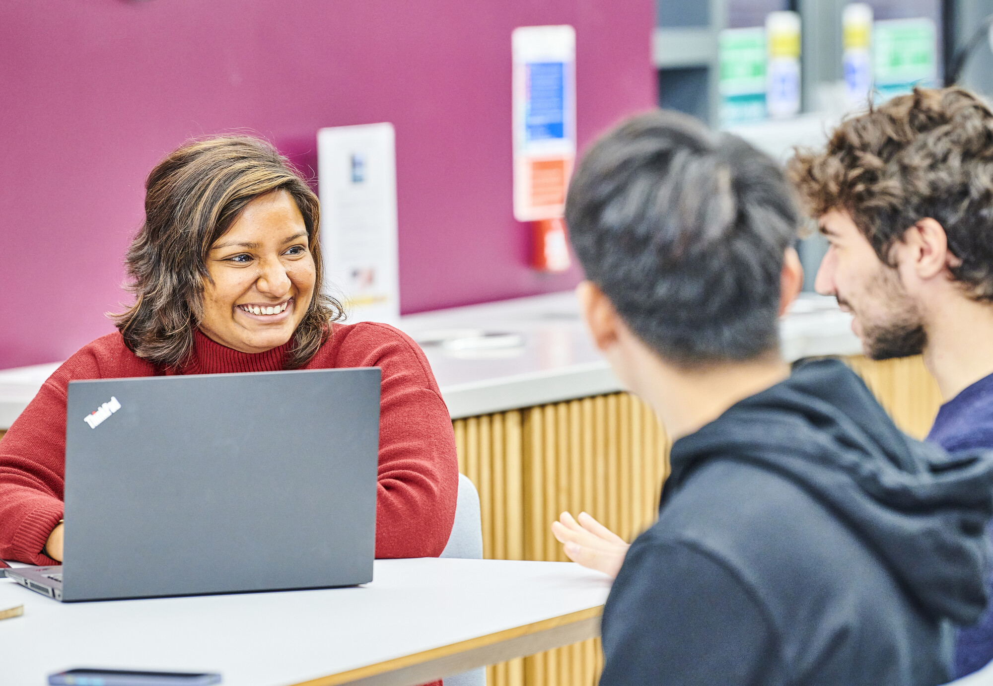 Three people talking with a laptop