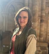Christina Bosbach stands in a cathedral on a sunny day, smiling at the camera.