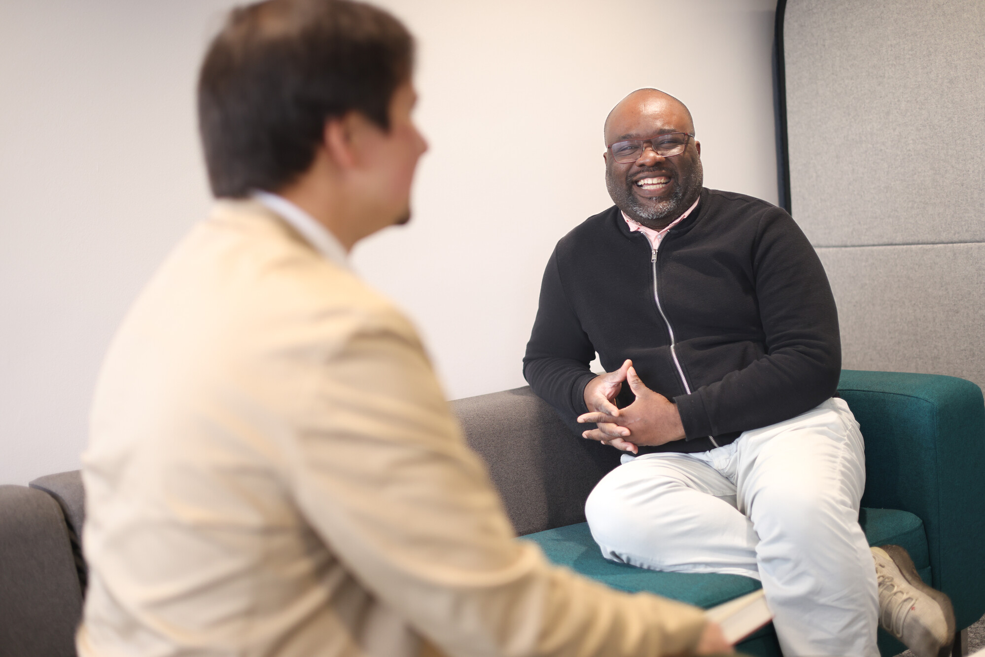 Two men sit talking and laughing