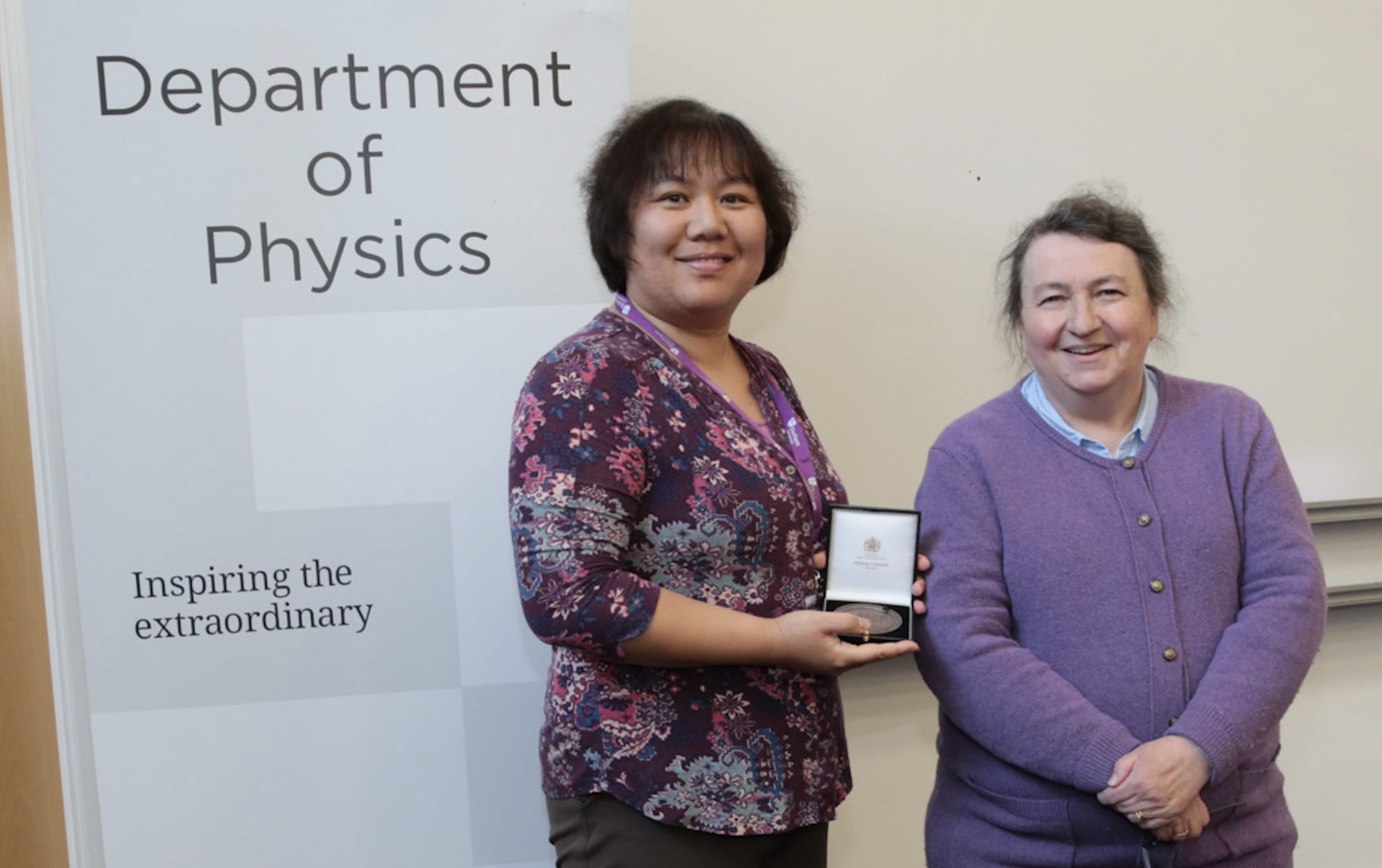 Lisa Qiao receiving a staff excellence award from Paula Chadwick