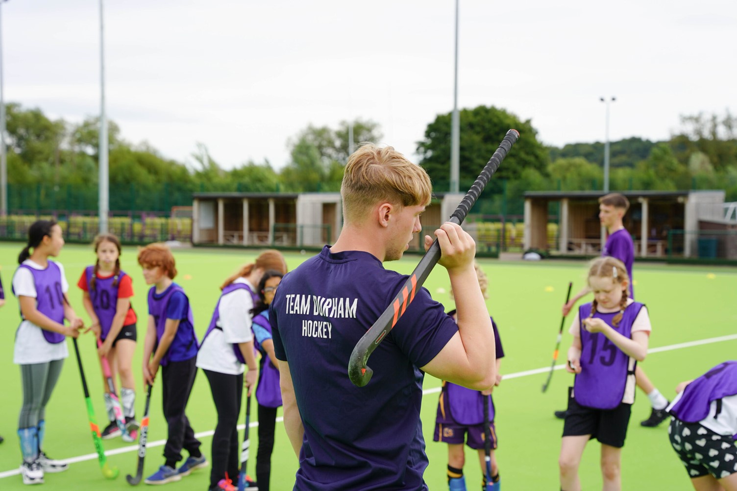 Student Jack with hocky stick over his shoulder facing away from camera