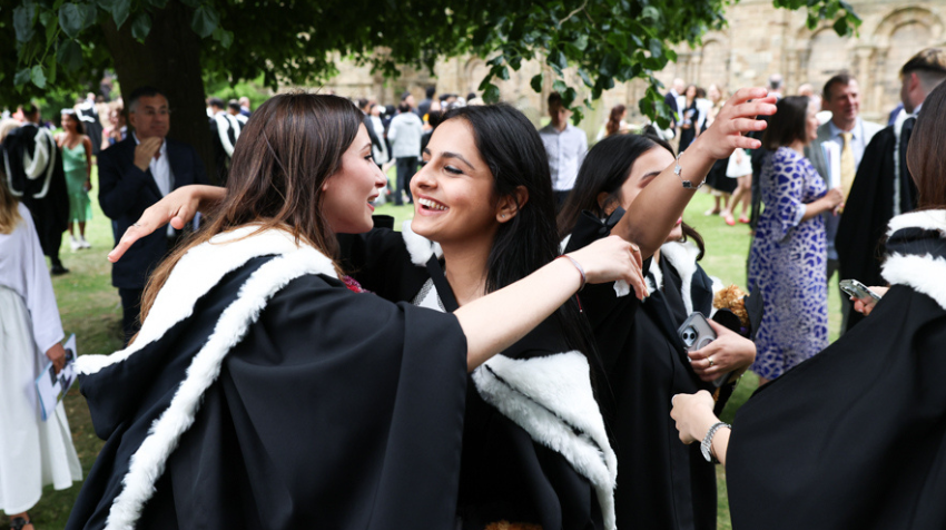 Students celebrating while wearing graduation robes