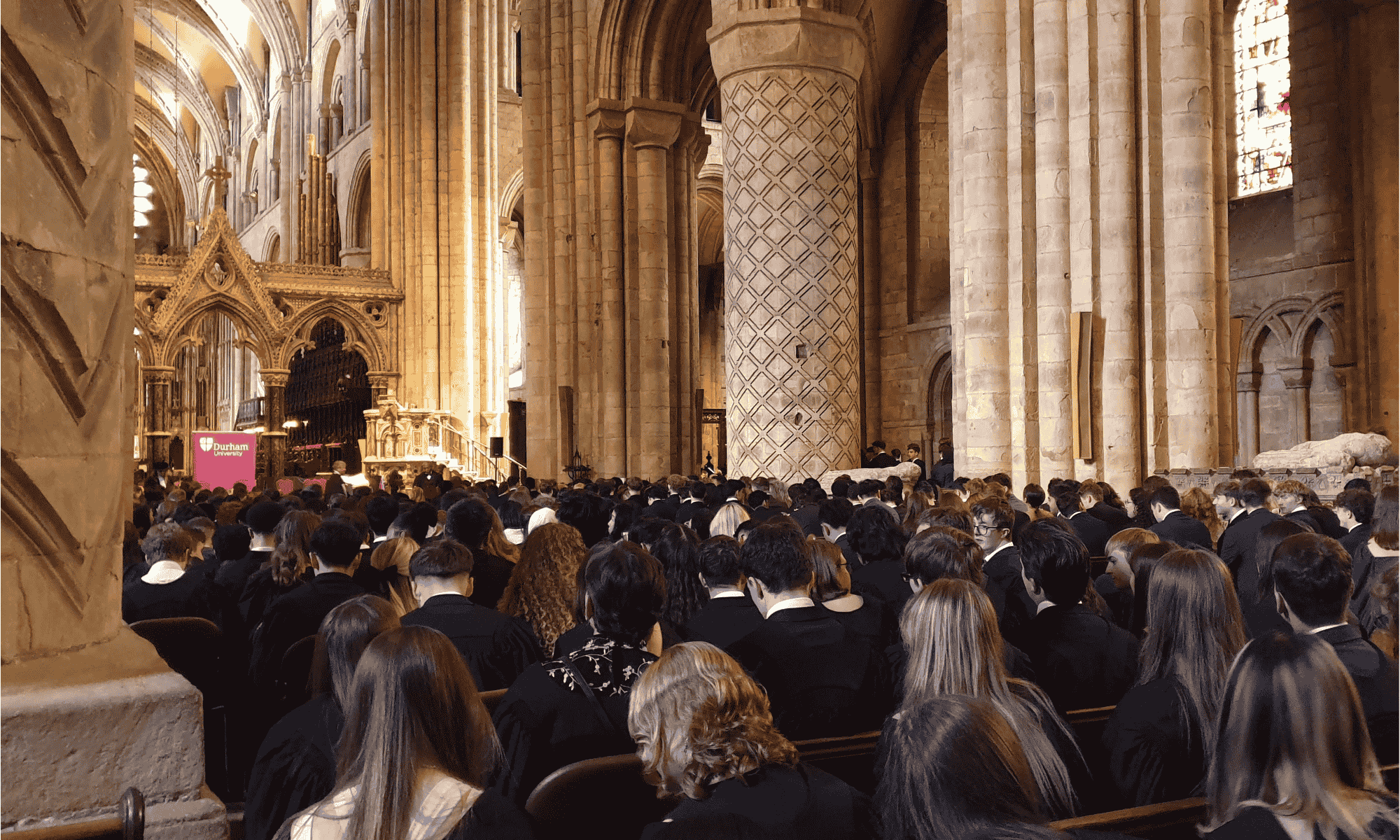 Students in robes sitting in Durham Cathedral Nave