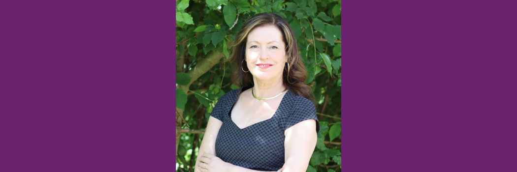 Professor Edith Hall is pictured with green leafy trees in the background