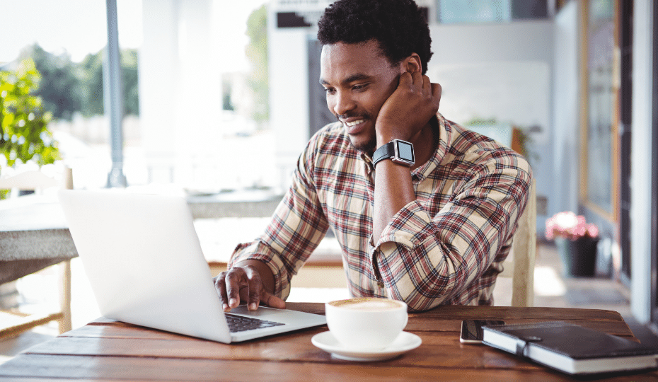 A man looking at a laptop with a cup of coffee