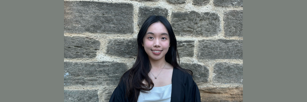 Cassie Yip smiles at the camera in front of a stone wall