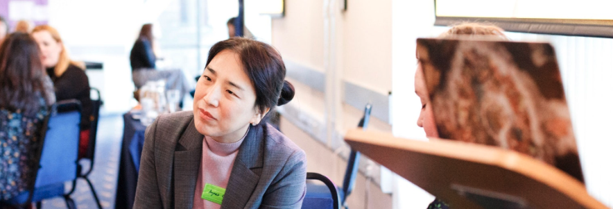 A researcher talking with another researcher in a workshop setting.