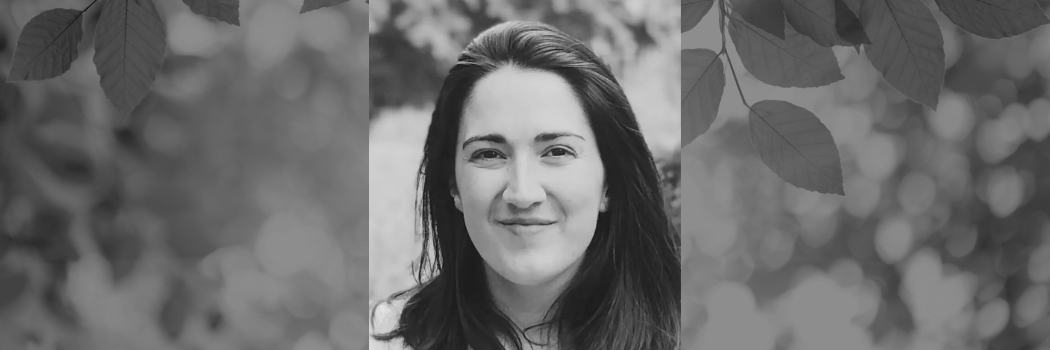 Black and white photograph of a dark-haired researching smiling at the camera.