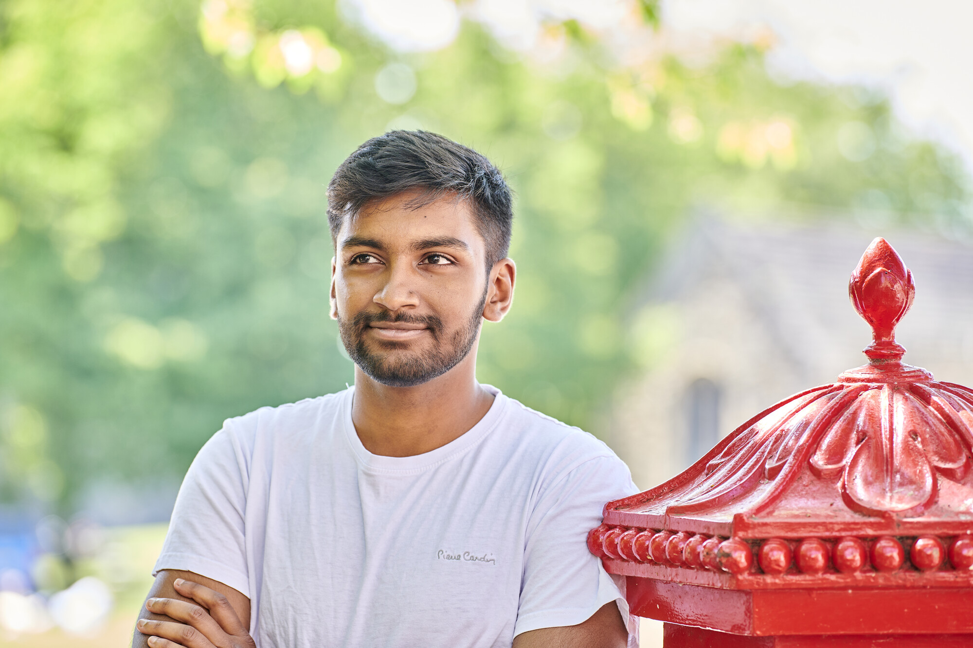 male student smiling beside red postbox