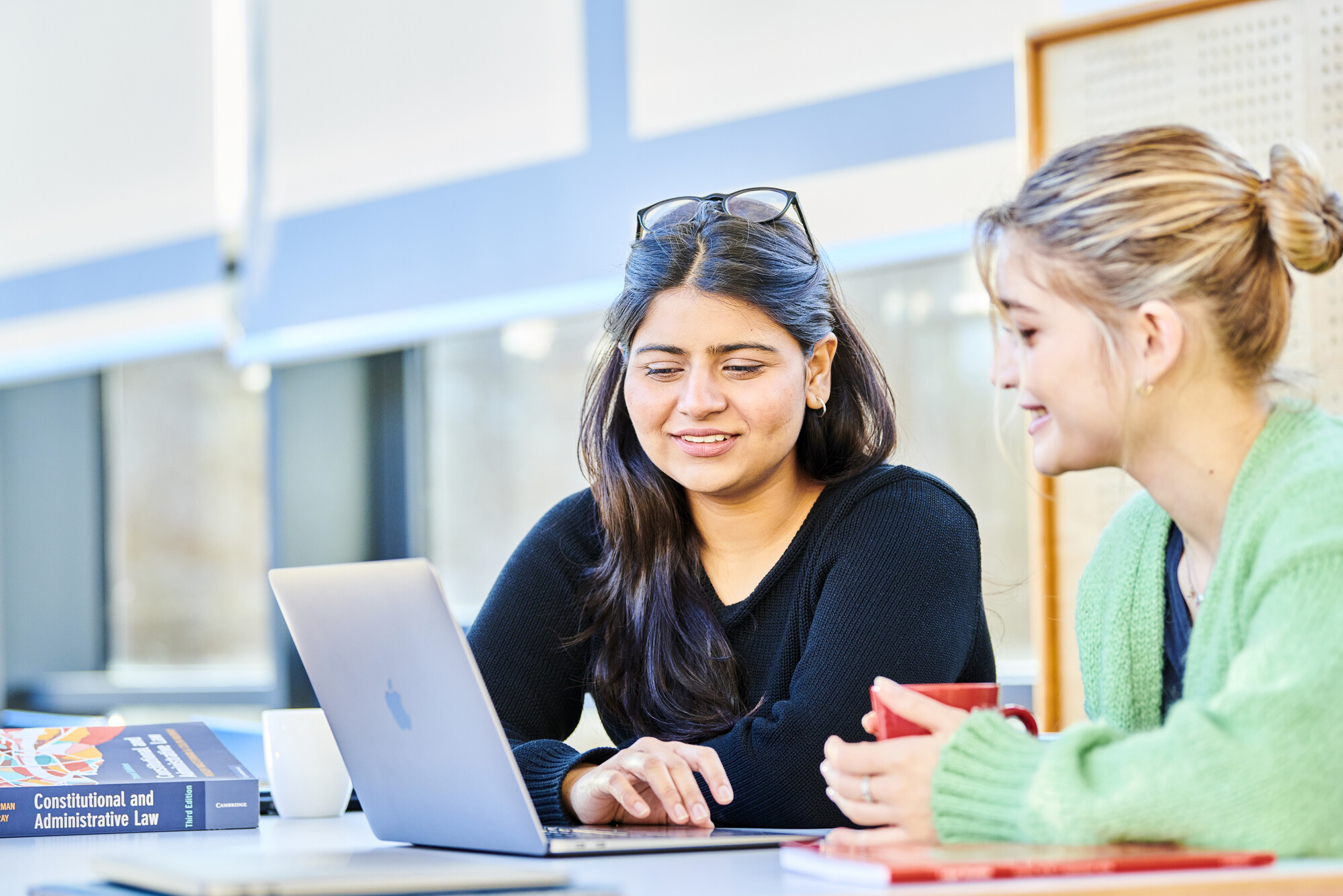 Law school undergraduates sit at the boardoom table in the Anne Galbraith Boardroom as they study and chat