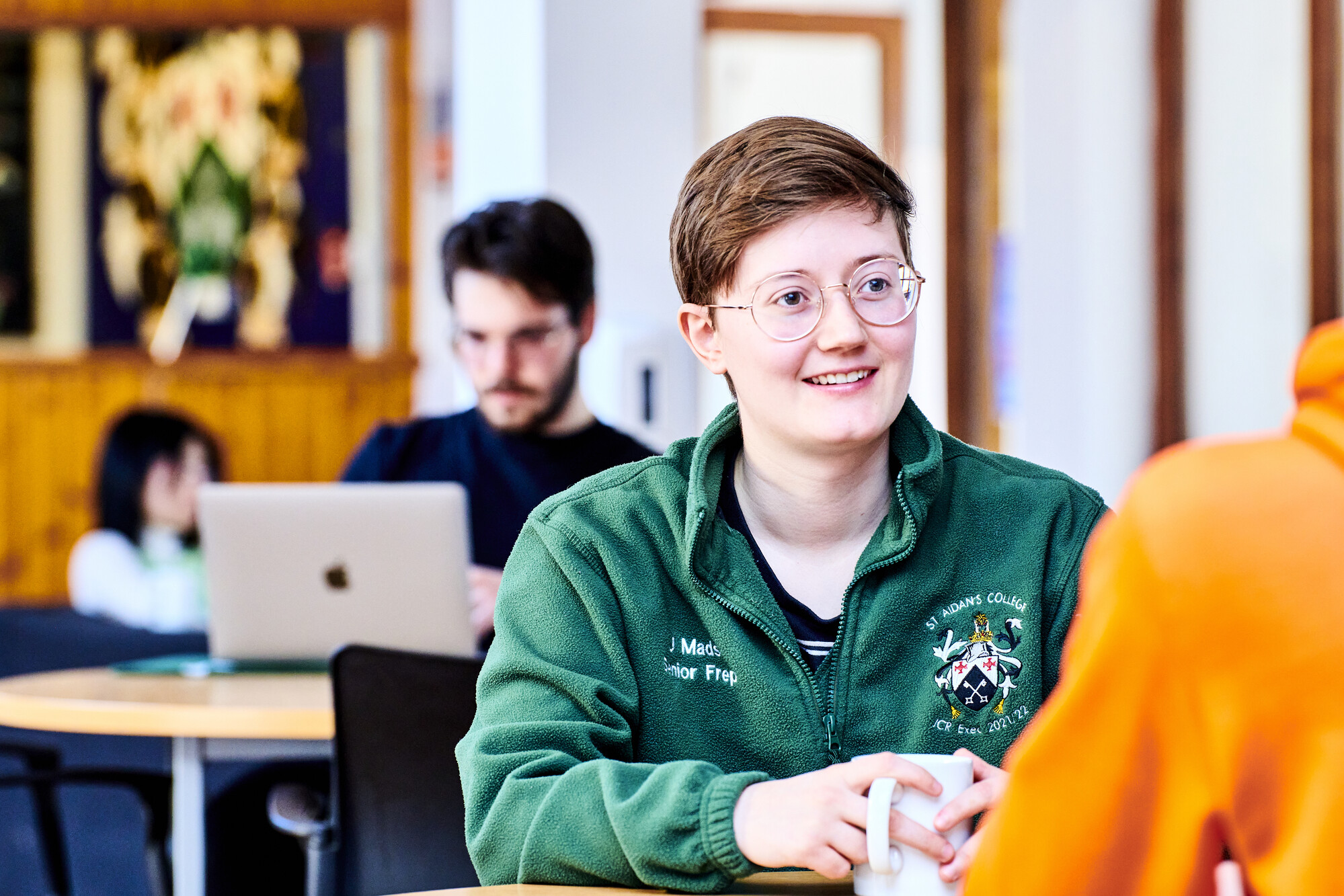Student in St Aidan's College fleece with a mug and smiling