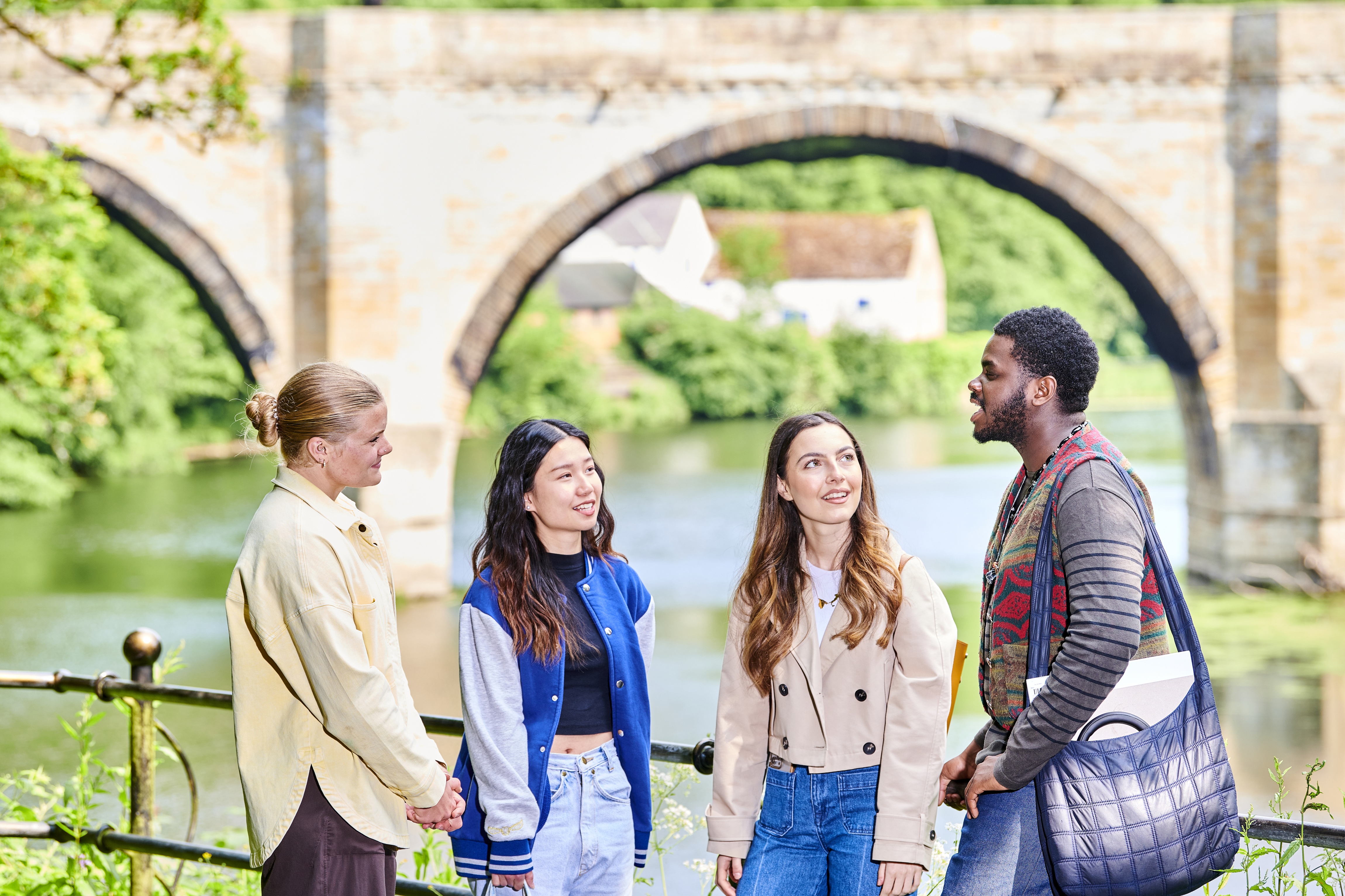 A group of four students smiling and chatting.