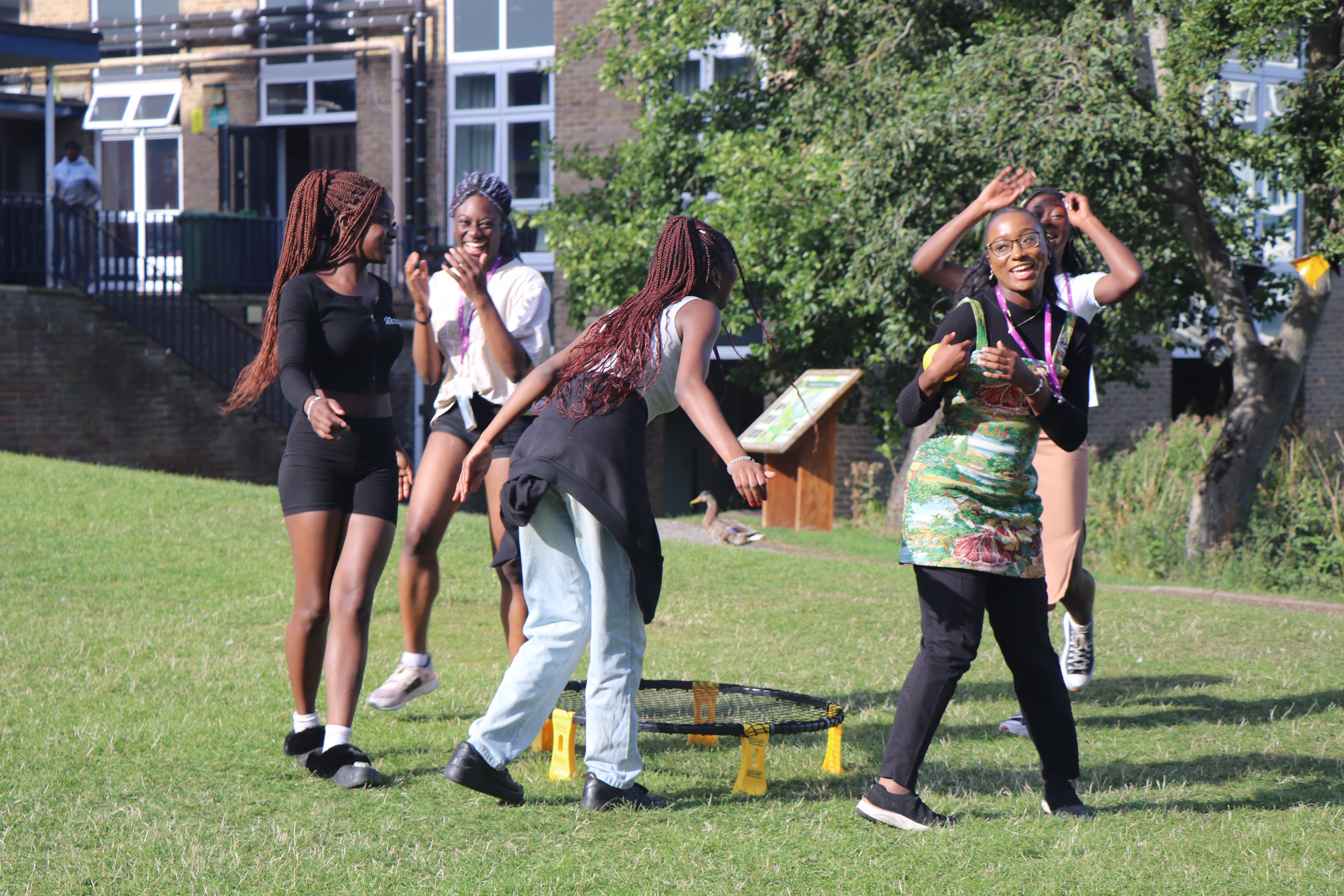 Five students playing spike ball, one is celebrating wile the others are laughing.