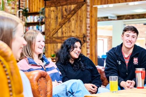 Group of male and female students drinking soft drinks, laughing and chatting