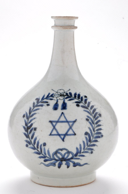 An oval shaped porcelain vessel with a long neck and blue decoration painted on the front